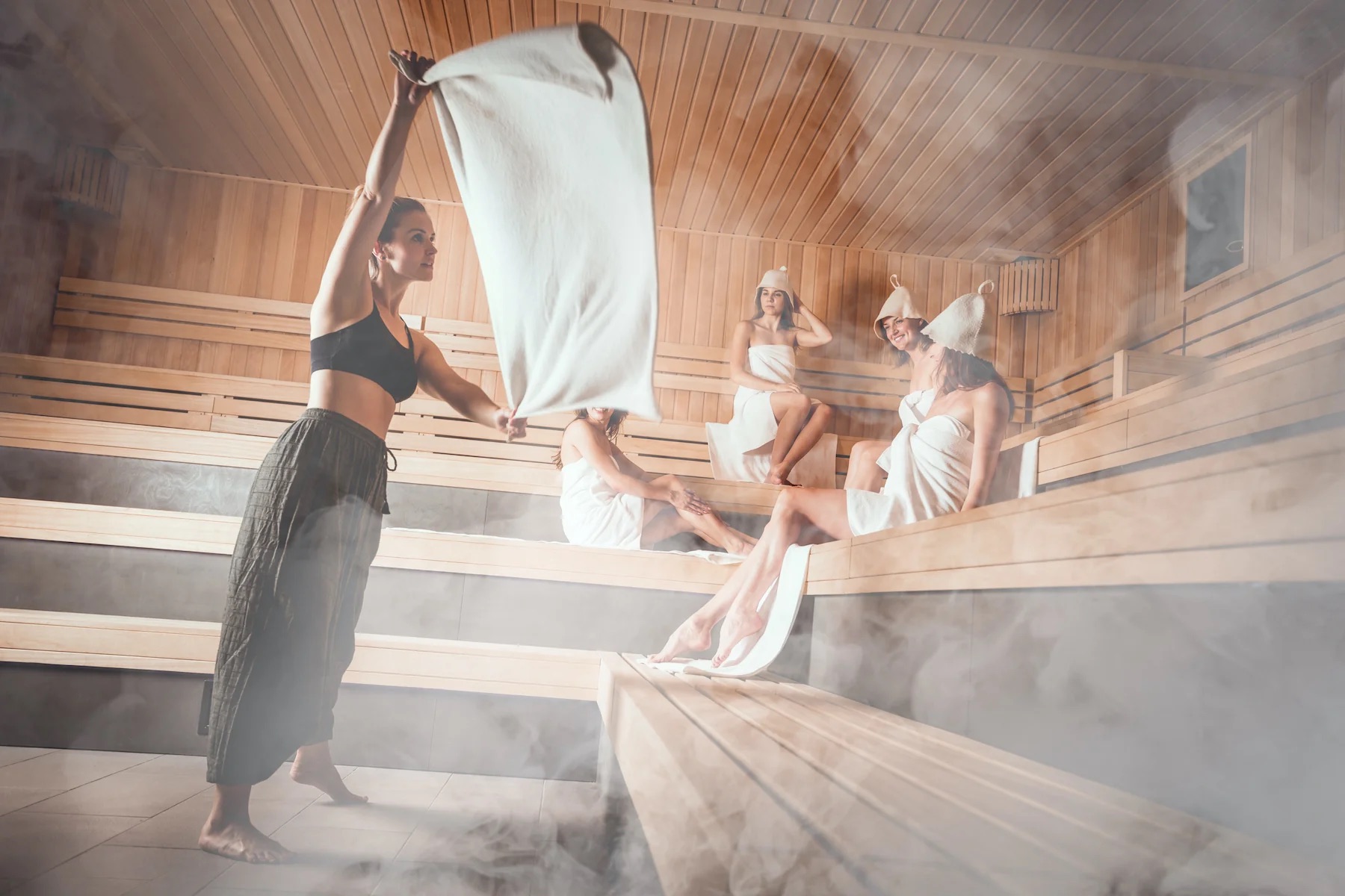 A sauna master leading an aufguss session, towel mid-wave through steam